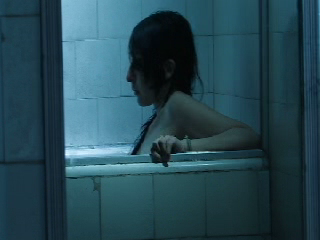 Eldos: la protagonista en la bañera vista en el espejo, rodeada por azulejos y luz fría